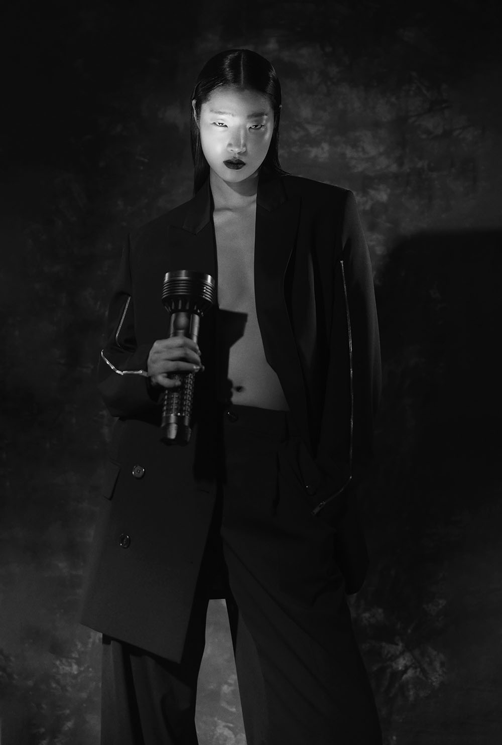 Fashion Photographer In Manhattan - Black and white fashion editorial of model in black suit holding flashlight with dramatic shadows by Vikram Pathak 
