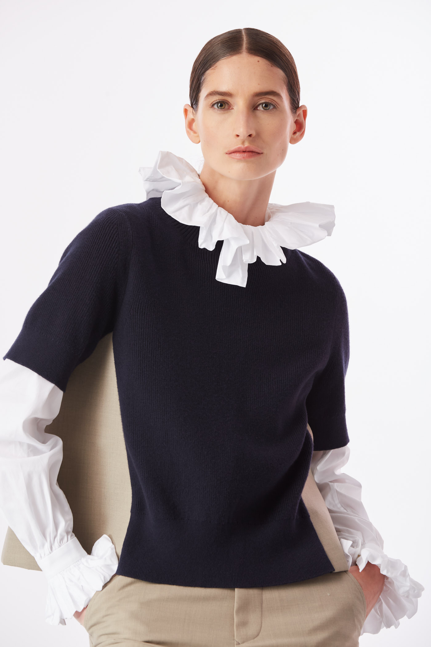 Model close-up wearing navy sweater layered over white ruffled collar shirt – New York fashion editorial