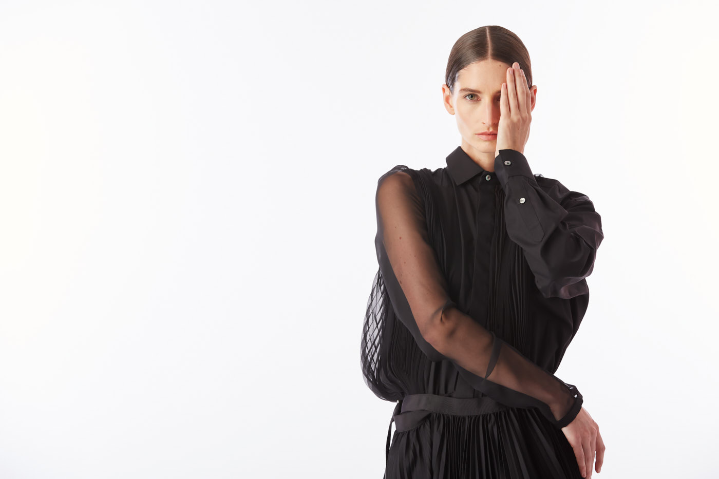 Model in sheer black long sleeve dress covering one eye – New York conceptual fashion editorial