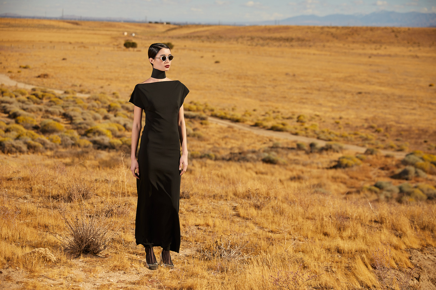 Model in black off-shoulder gown standing in desert field, photographed by fashion photographer Vikram Pathak
