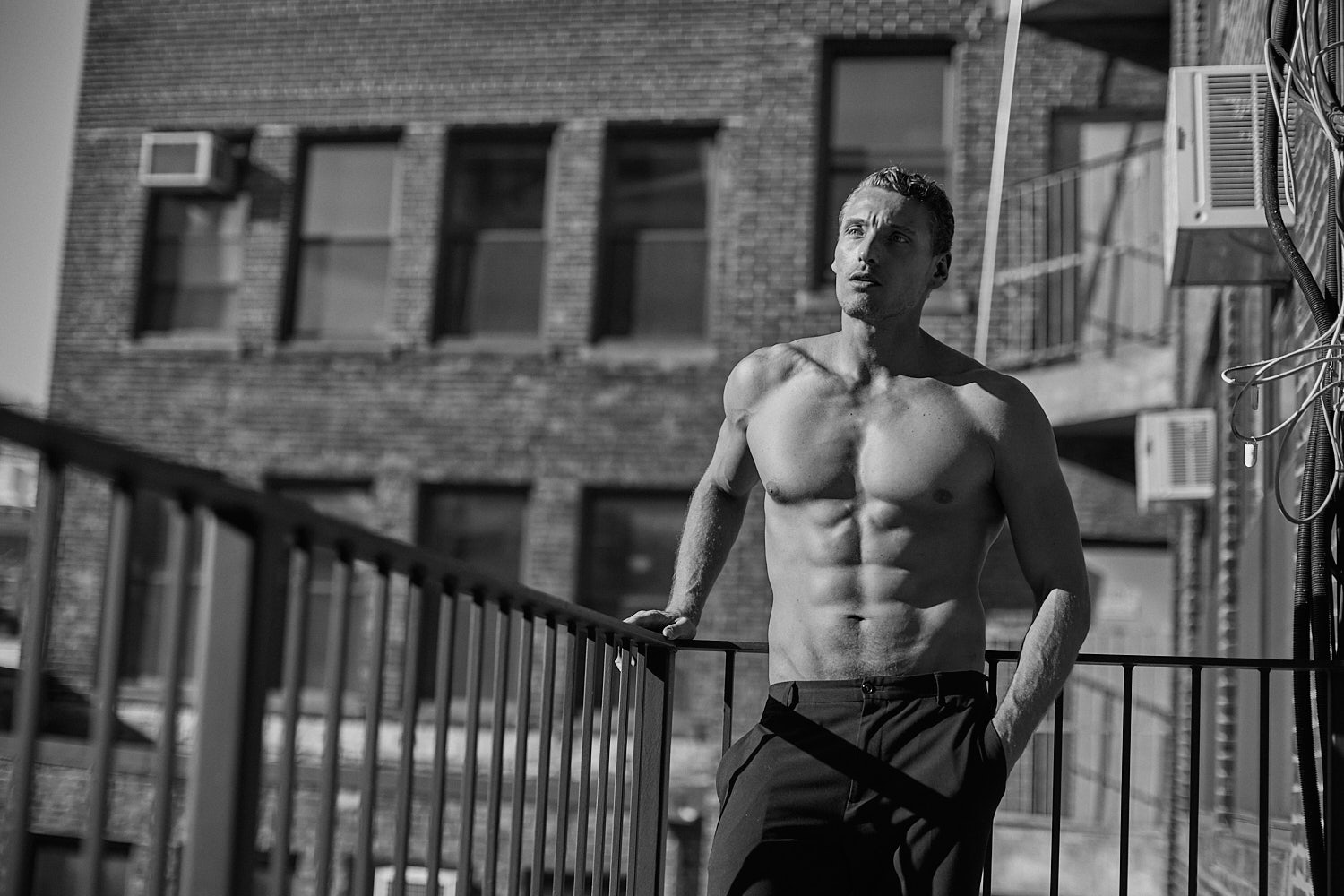 Male fitness model posing shirtless on New York balcony by Vikram Pathak