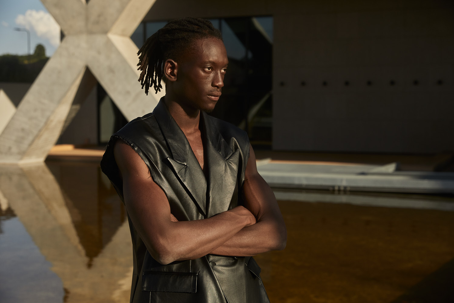 Close-up portrait of male model in sleeveless black leather suit under natural sunlight, photographed by Vikram Pathak.