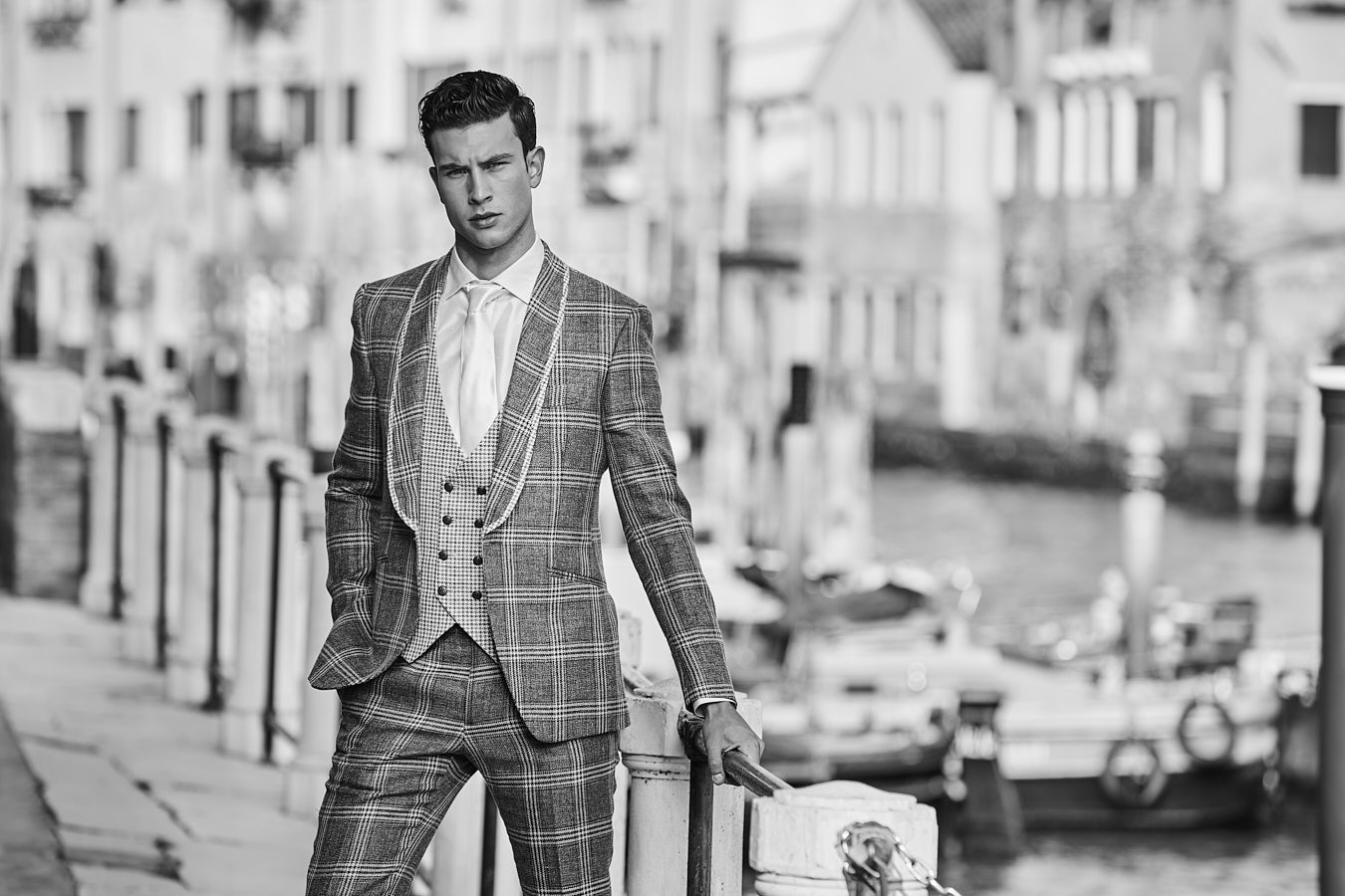 Full-length portrait of a man in Black and white plaid suit near canal.