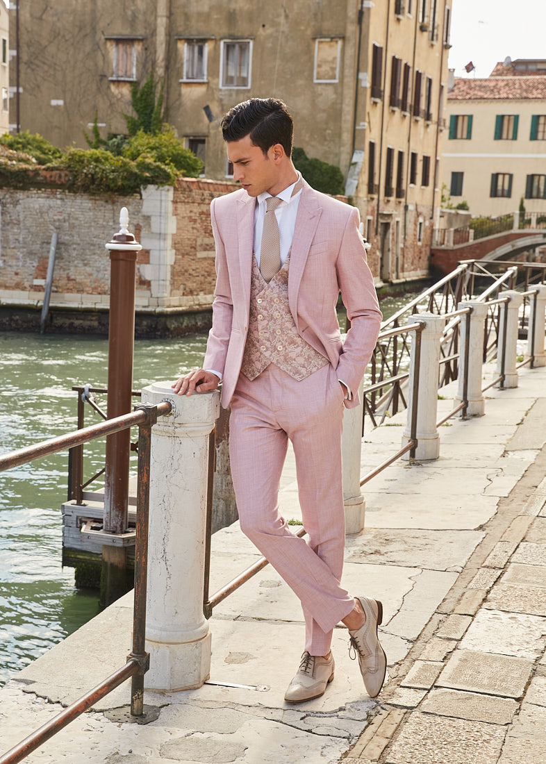 Male model wearing a pastel pink tailored suit in Venice, styled for a luxury menswear editorial.