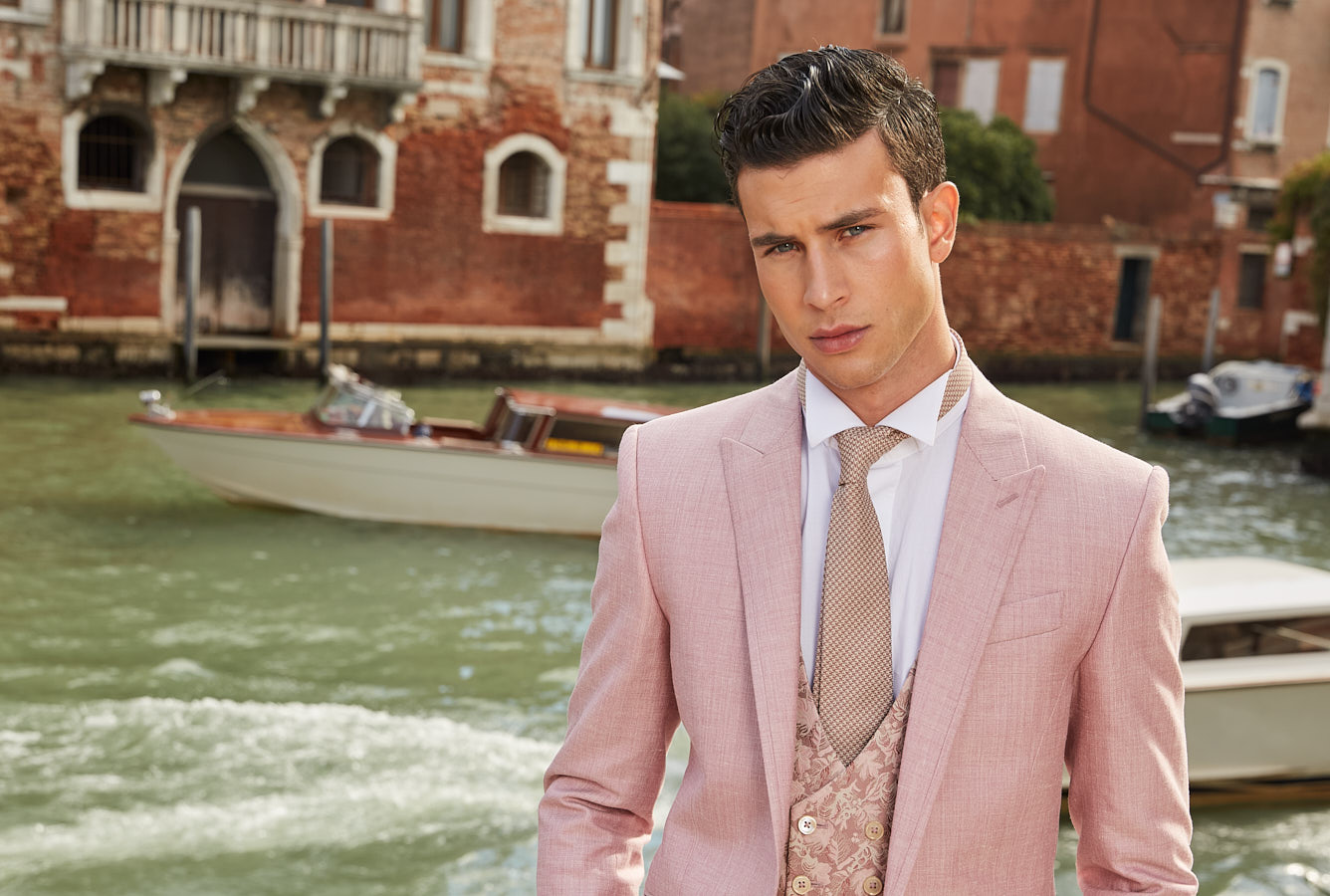 Close-up of model in pink suit with patterned vest and tie in Venice.