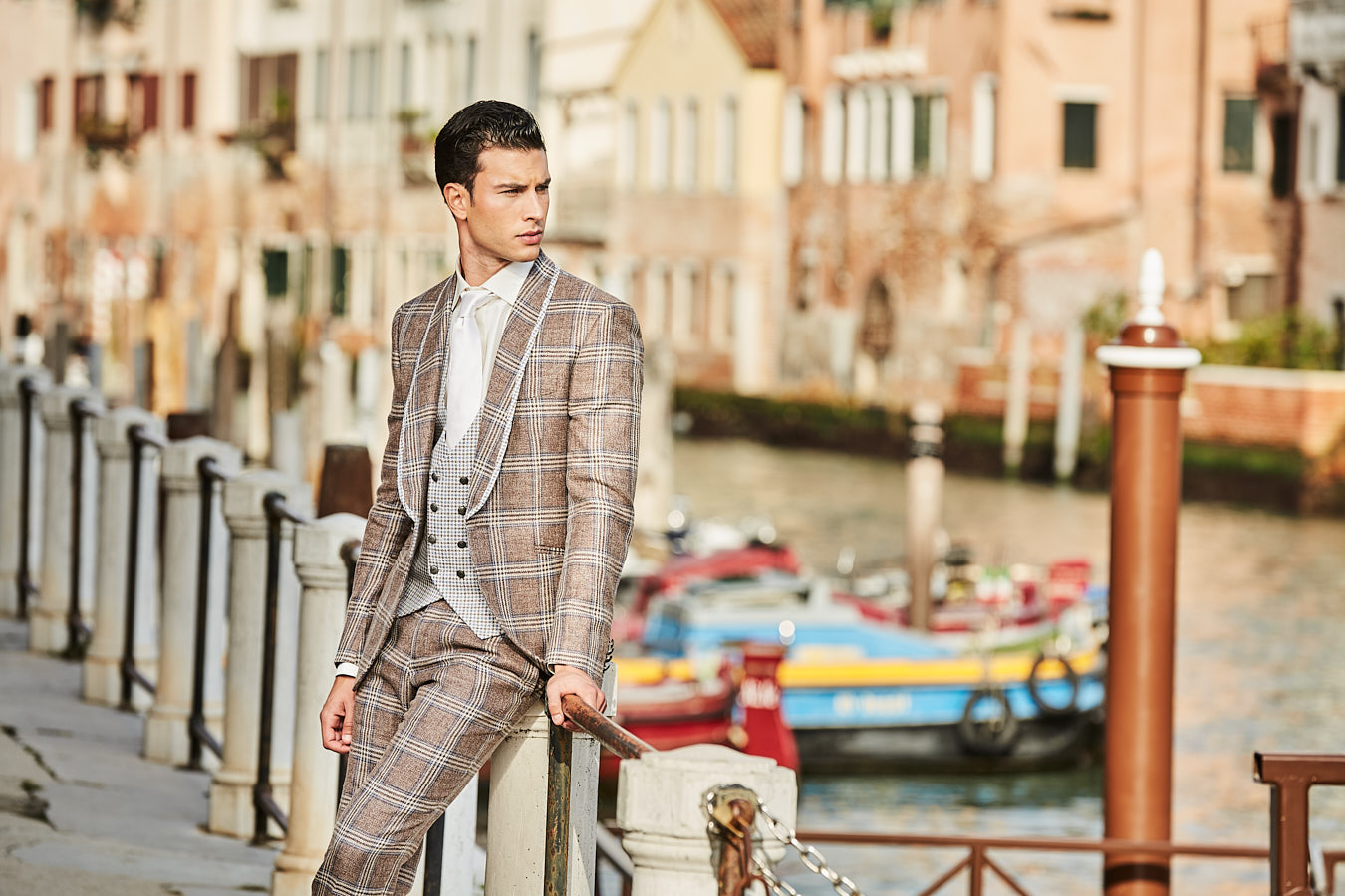 Model in brown plaid suit posing by a canal in Venice.