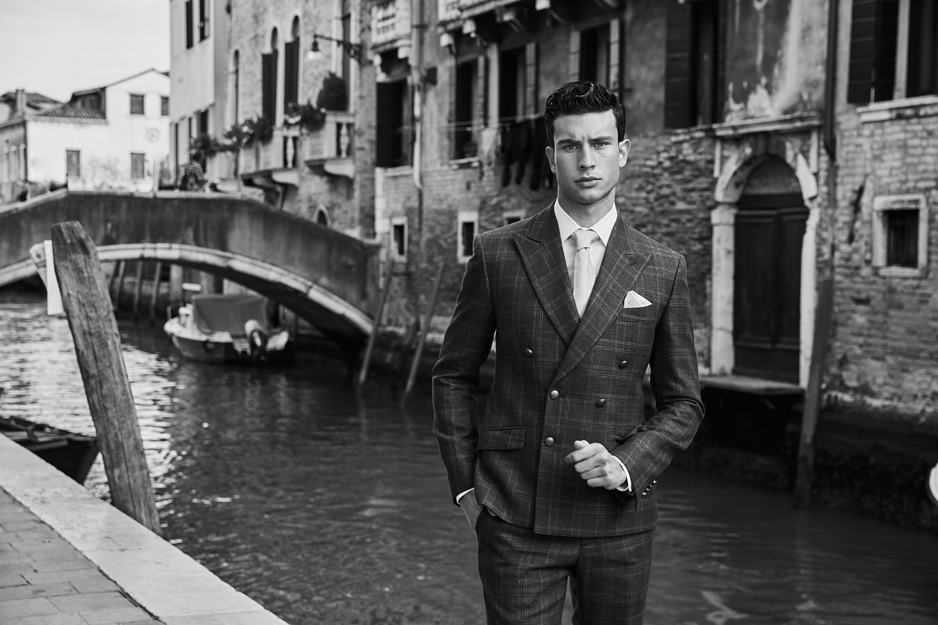 Male model in tailored plaid suit near bridge in Venice