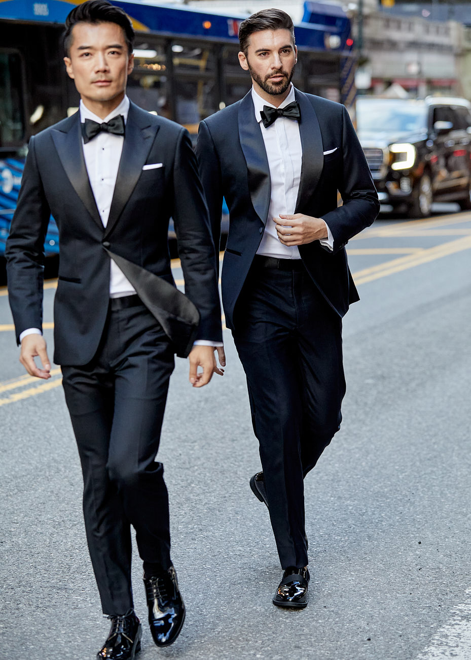 Two male models in black tuxedos walking through NYC street during high-end editorial shoot by Vikram Pathak